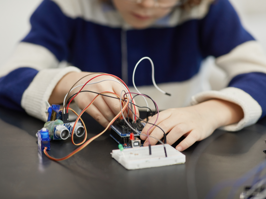 Menino montando circuito em arduino - o que são aulas de robótica